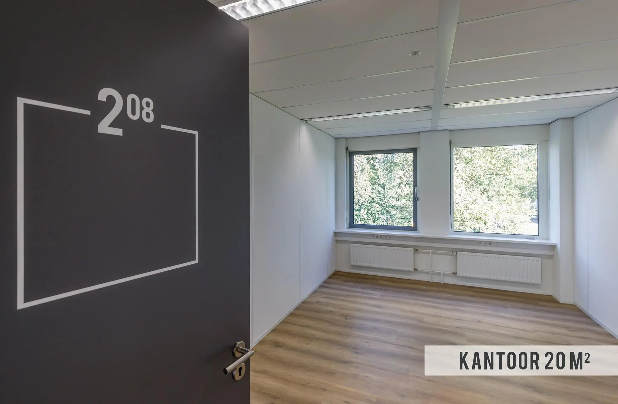 Licht en leeg kantoor van 20 m² met houten vloer en twee grote ramen aan de Baarnsche Dijk.